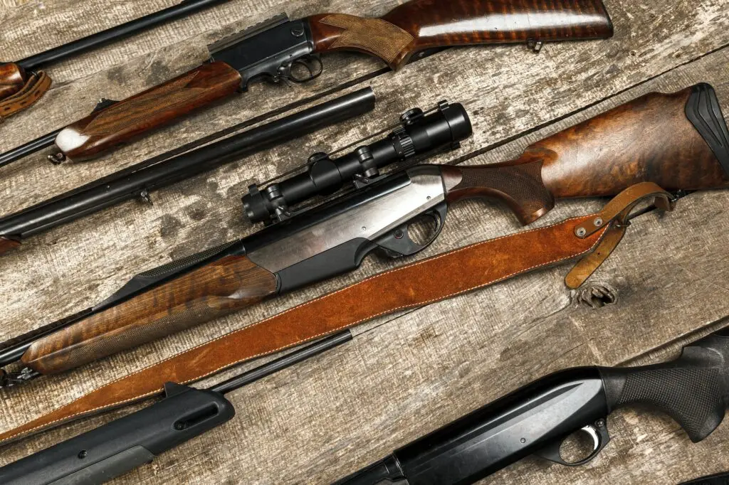 Many hunting rifles on weathered wooden surface