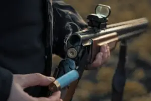 Sports shooting. Hunter reloading shotgun pellets cartridge. Smoke from the trunks of smooth-bore hunting rifle