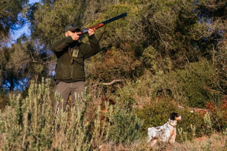 Male hunter shooting from gun during hunt with dog