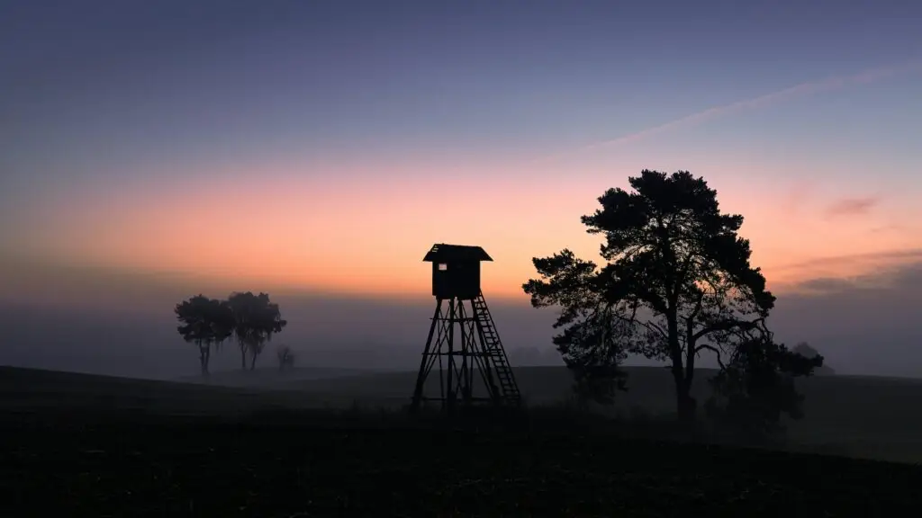 Silhouette of a hunting tower on a field in at dawn.